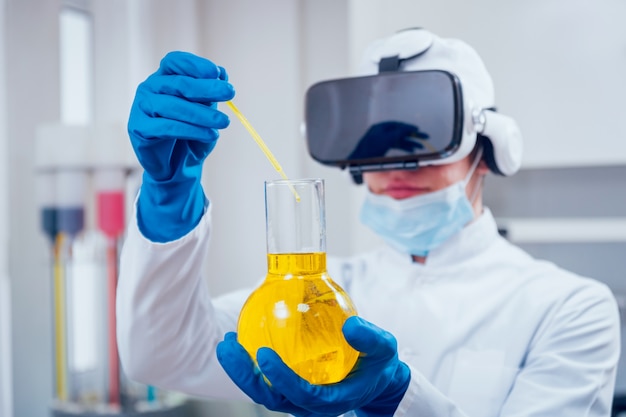 Un technicien scientifique en lunettes de réalité virtuelle examine le médicament en laboratoire.