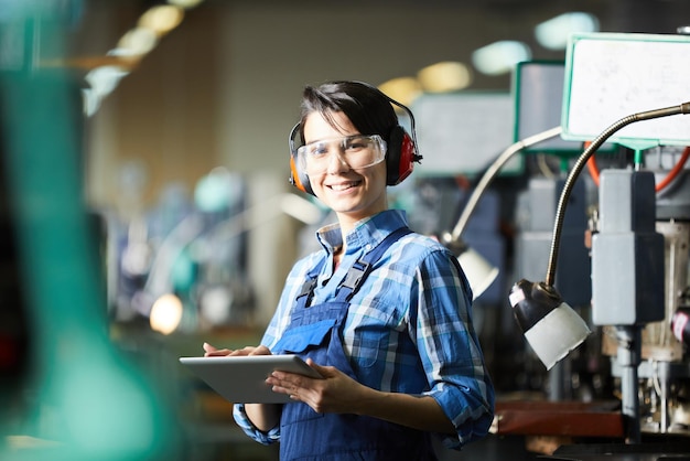 Technicien souriant utilisant une tablette à l'usine