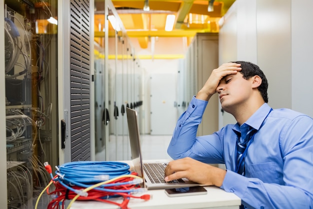 Technicien stressé travaillant un ordinateur portable