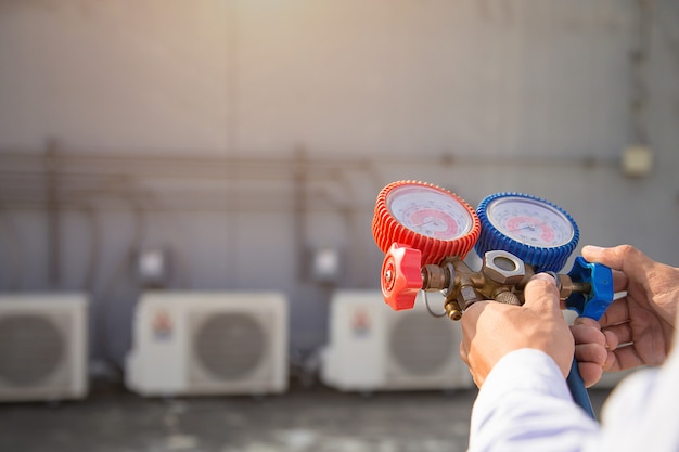 Technicien utilisant un équipement de mesure pour le remplissage de climatiseurs industriels en usine.