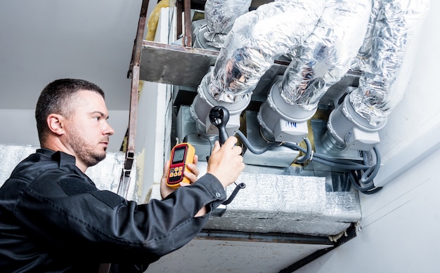 Le technicien utilise un anémomètre portatif mesurant la mesure du débit d'air, la vitesse du vent et la pression.