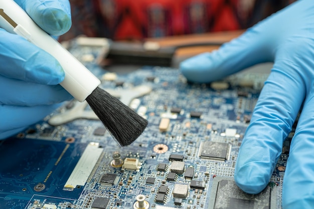 Le technicien utilise une brosse et une boule de soufflage d'air pour nettoyer la poussière dans l'ordinateur de carte de circuit imprimé