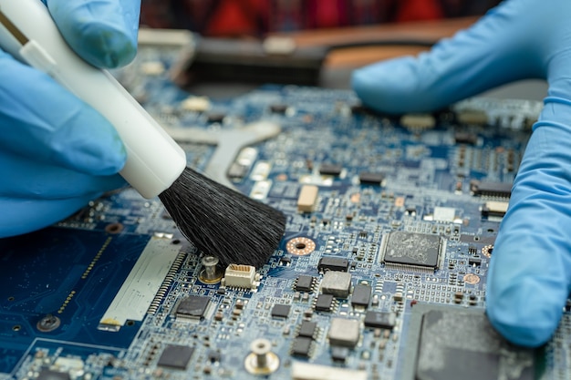 Le technicien utilise une brosse et une boule de soufflage d'air pour nettoyer la poussière dans l'ordinateur de carte de circuit imprimé