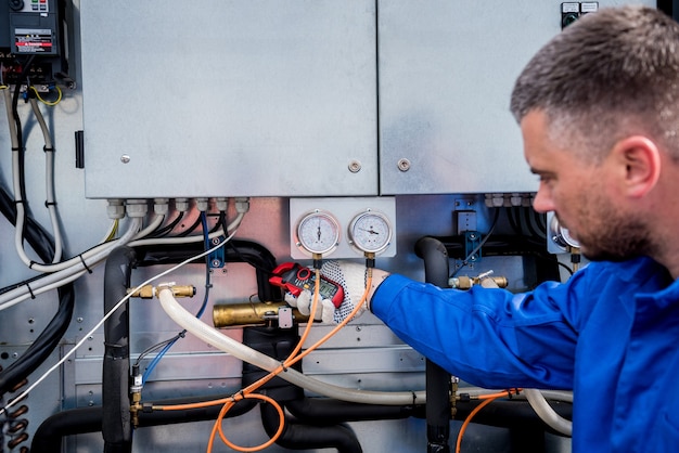 Le technicien vérifiant les lignes électriques de l'échangeur de chaleur avec des pinces de courant