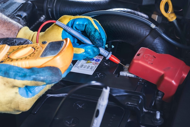 Technicien vérifiant la stabilité de la tension continue de la batterie de la voiture avec une sonde multimètre numérique