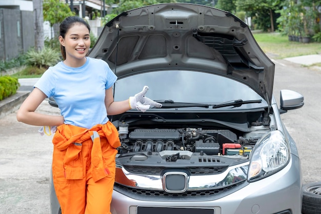 Techniciennes automobiles asiatiques en uniforme debout tout en pointant quelque chose