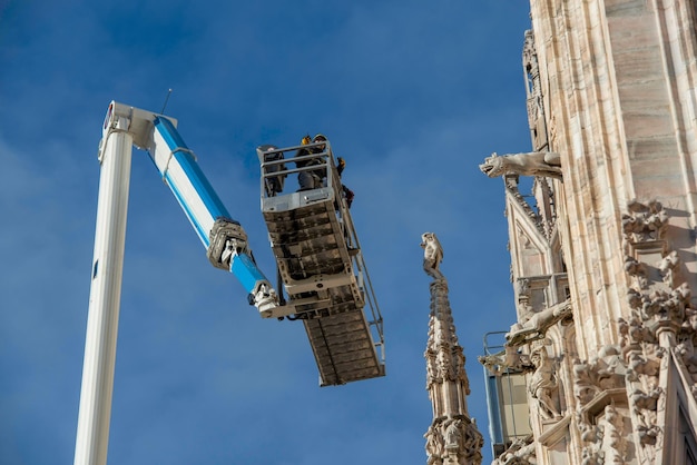 Techniciens sur plateforme élévatrice pour plan de maintenance programmé et étude des phénomènes de dégradation de la cathédrale de Milan