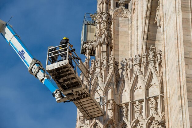 Techniciens sur plateforme élévatrice pour plan de maintenance programmé et étude des phénomènes de dégradation de la cathédrale de Milan
