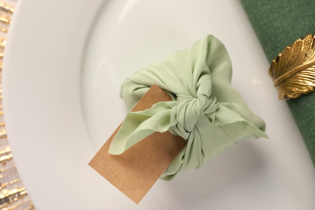 Technique de furoshiki Cadeau emballé dans une carte vierge en tissu vert et une serviette sur la vue de dessus de la plaque