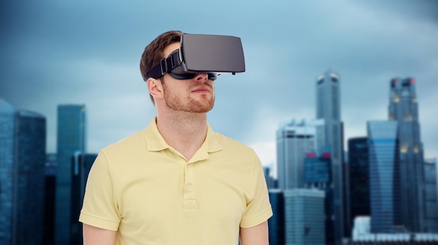 Technologie 3d, réalité virtuelle, concept de divertissement et de personnes - jeune homme avec casque de réalité virtuelle ou lunettes 3d sur fond de gratte-ciel de la ville de singapour