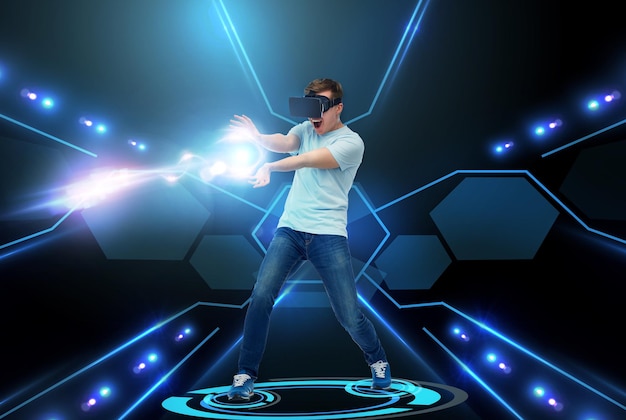 Technologie 3d, réalité virtuelle, divertissement, cyberespace et concept de personnes - jeune homme heureux dans un casque de réalité virtuelle ou des lunettes 3d jouant avec un rayon de lumière laser sur fond noir