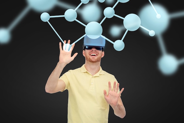 Technologie 3d, réalité virtuelle, science, biologie et concept humain - jeune homme heureux avec casque de réalité virtuelle ou lunettes 3d jouant au jeu sur fond noir et molécules