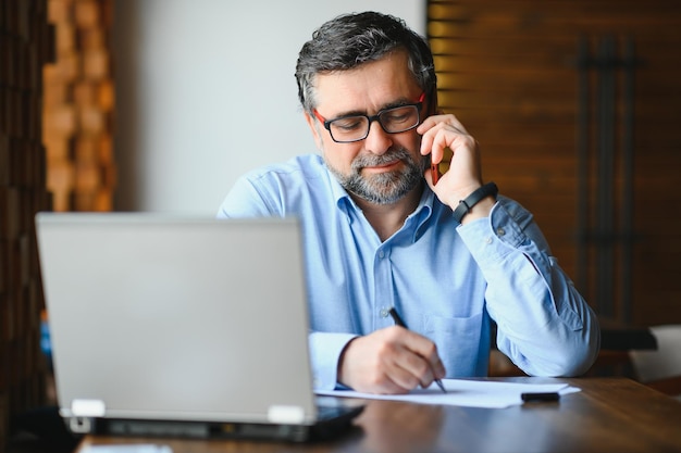 Technologie d'entreprise et concept de personnes homme d'affaires senior avec ordinateur portable, boire du café au café moderne