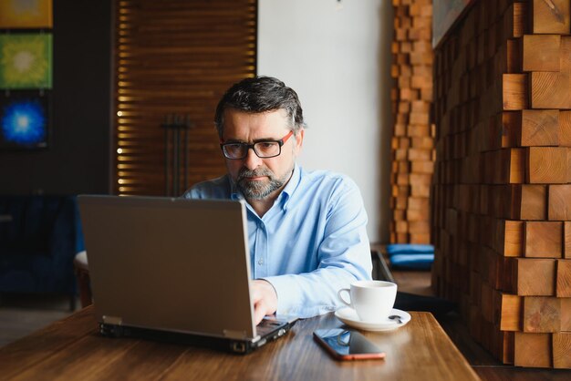 Technologie d'entreprise et concept de personnes homme d'affaires senior avec ordinateur portable, boire du café au café moderne