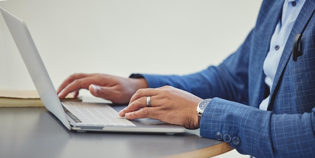 La technologie fait partie des affaires modernes Photo recadrée d'un homme d'affaires méconnaissable assis seul dans son bureau et utilisant son ordinateur portable