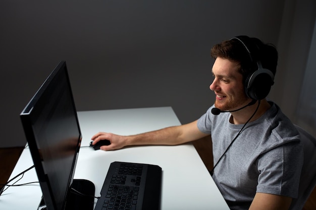 technologie, jeux, divertissement, jouons et concept de personnes - jeune homme heureux dans un casque avec ordinateur pc jouant à la maison et diffusion en continu ou vidéo pas à pas