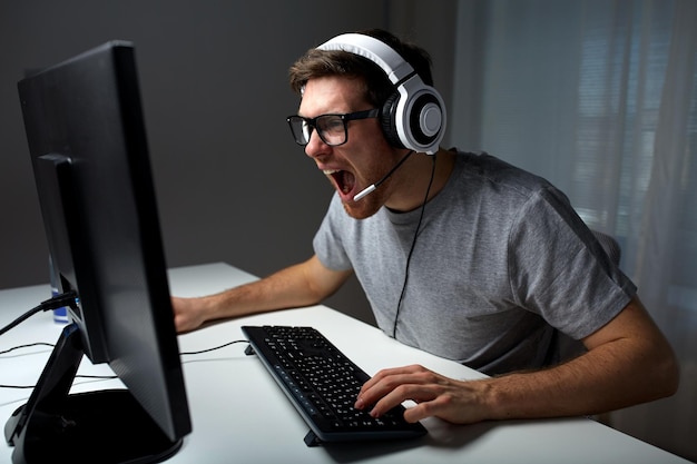 technologie, jeux, divertissement, jouons et concept de personnes - jeune homme hurlant de colère dans un casque avec ordinateur pc jouant à la maison et diffusion en continu ou vidéo pas à pas