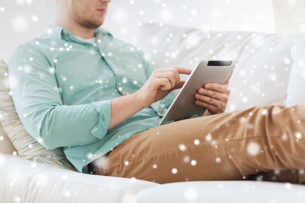 technologie, loisirs, personnes et concept d'apprentissage à distance - gros plan d'un homme travaillant avec un ordinateur tablette assis sur un canapé à la maison