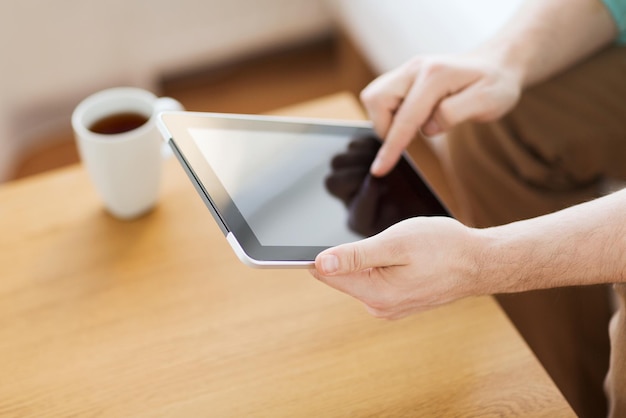 technologie, maison, boissons et concept de style de vie - gros plan sur un homme avec un ordinateur tablette et une tasse de café à la maison