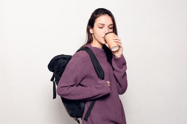 Technologie, mode de vie, dépendance à Internet et concept de personnes - Belle jeune femme avec un téléphone intelligent. Femme séduisante heureuse et souriante en regardant le téléphone portable. Mur gris à l'arrière-plan.