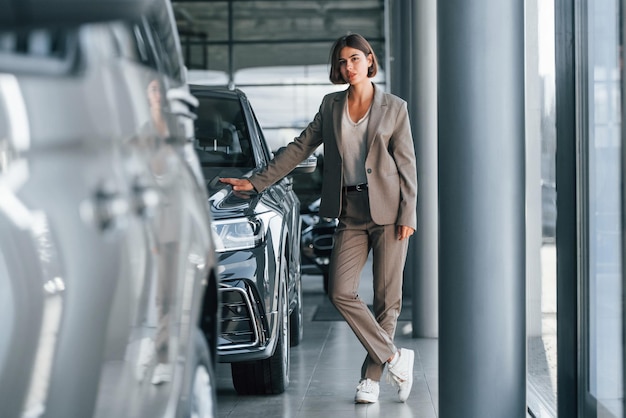 Technologie moderne La femme est à l'intérieur près d'une nouvelle automobile à l'intérieur