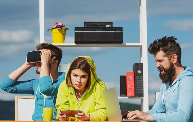 Technologie moderne Jeunes hommes et femmes assis à une table avec des lunettes de réalité virtuelle Équipe commerciale