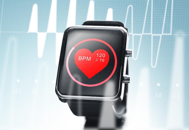 Photo technologie moderne, objet, soins de santé et concept médiatique - gros plan d'une montre intelligente noire montrant une icône de battement de coeur rouge à l'écran et un cardiogramme