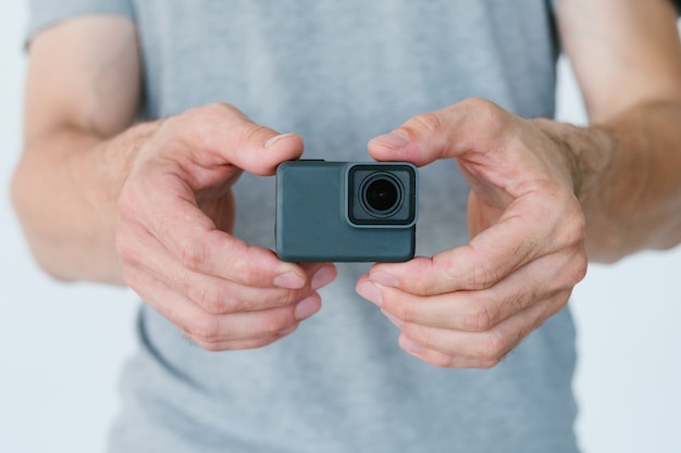 Technologie moderne pour la création de contenu vidéo. homme méconnaissable tenant une caméra d'action dans les mains. concept d'équipement et d'outils de blogueur.