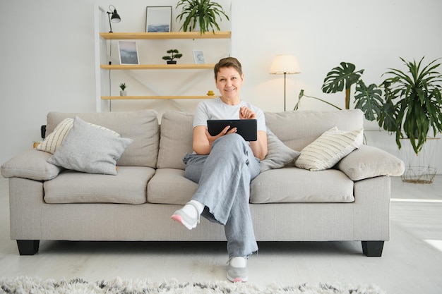 Technologie des personnes et concept internet heureuse femme d'âge moyen avec tablette pc à la maison