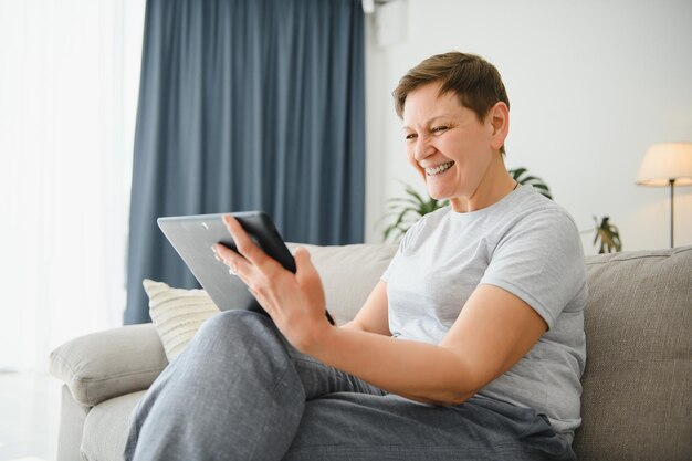 Technologie des personnes et concept internet heureuse femme d'âge moyen avec tablette pc à la maison