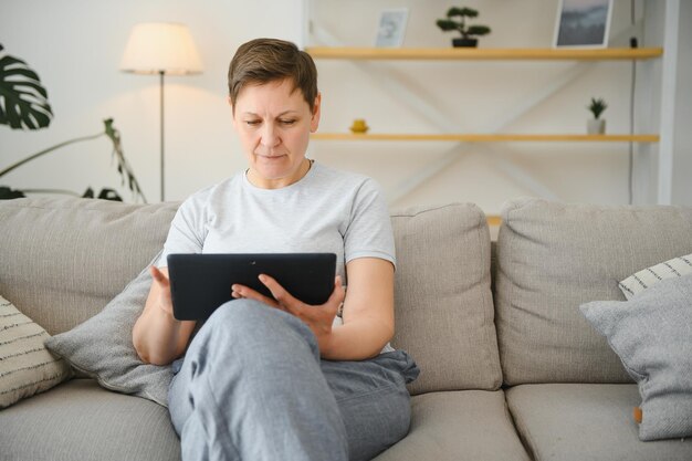 Technologie des personnes et concept internet heureuse femme d'âge moyen avec tablette pc à la maison