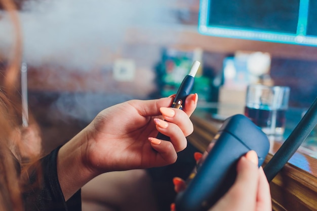 technologie de produit du tabac non brûlé par la chaleur femme tenant une e-cigarette dans sa main avant de fumer