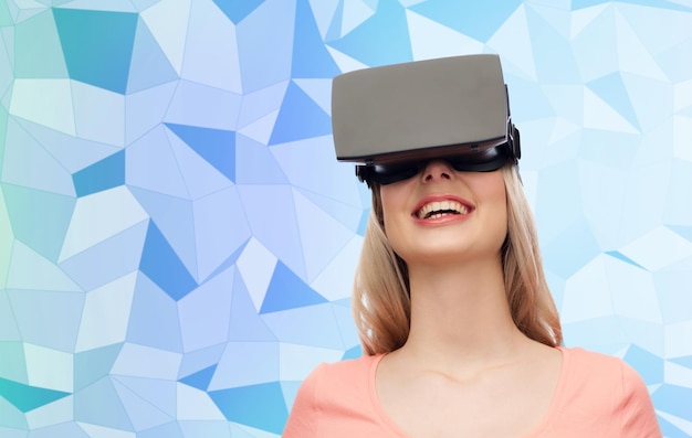 technologie, réalité virtuelle, divertissement et concept de personnes - jeune femme heureuse avec casque de réalité virtuelle ou lunettes 3d sur fond de texture bleu low poly