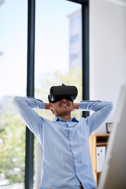 La technologie rend sa vie tellement plus facile Photo d'un jeune homme d'affaires heureux portant un casque de réalité virtuelle tout en travaillant à son bureau au bureau