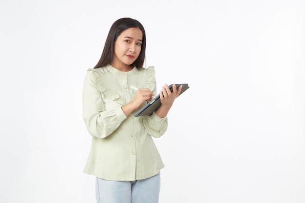 Technologie sans fil. Belle jeune femme asiatique tenant une tablette numérique et regardant la caméra avec le sourire en se tenant debout isolé sur fond blanc.