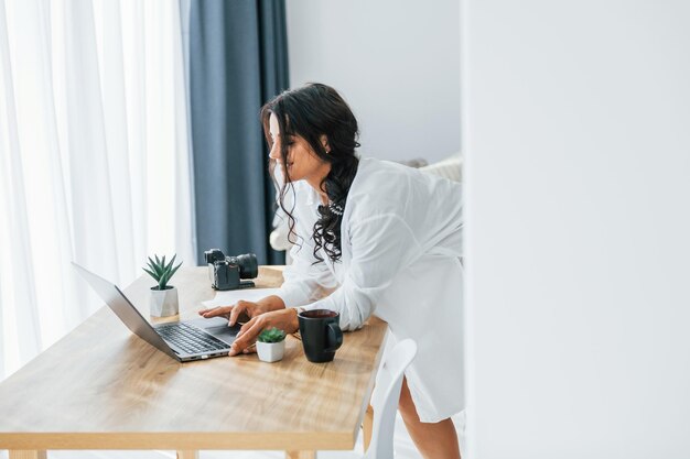 Technologie sans fil Utilise un ordinateur portable Une femme en vêtements décontractés est à l'intérieur à la maison