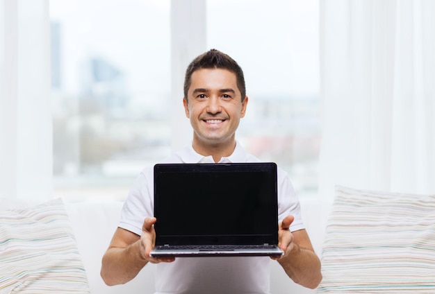 technologie, style de vie des gens et concept de mise en réseau - homme heureux montrant un écran noir d'ordinateur portable à la maison