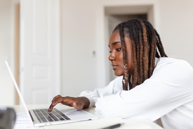 Photo technologie de travail à distance et concept de personnes jeune femme d'affaires africaine avec ordinateur portable et papiers travaillant au bureau à domicile pendant la crise sanitaire de covid19