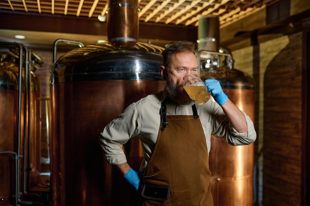 Technologue en brasserie dégustant de la bière artisanale fraîche dans une microbrasserie