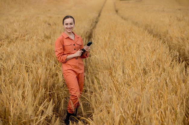 Technologue caucasienne agronome avec tablette dans le domaine du blé vérifiant la qualité et la croissance des cultures pour l'agriculture. Concept d'agriculture et de récolte.