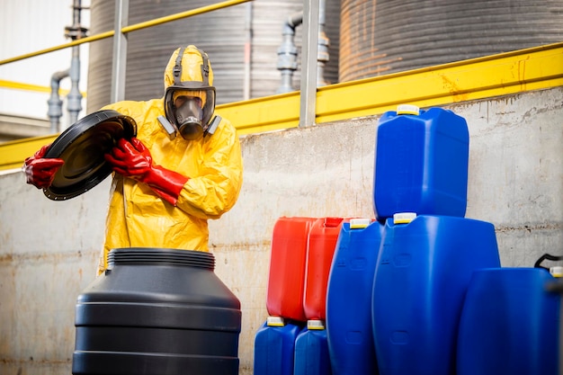 Technologue en chimie en costume de matières dangereuses et masque à gaz ouvrant le baril avec des substances agressives