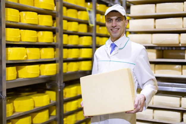 Un technologue avec du fromage dans les mains effectue une inspection de la production prête au département de l'usine laitière