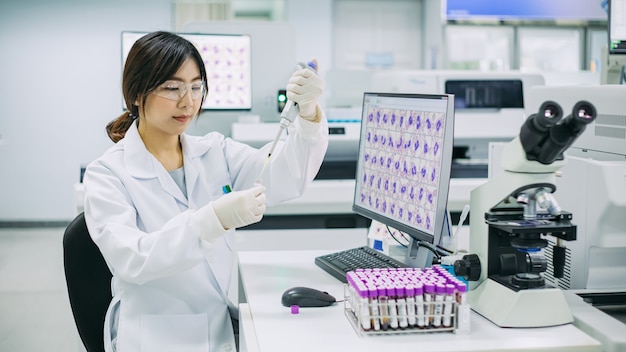 Technologue médical pipetage avec des échantillons de sang des tubes à essai en laboratoire