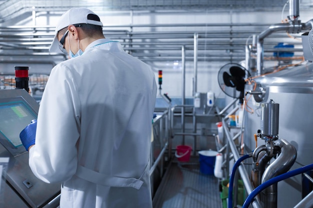 Photo un technologue prépare la chaîne de production tout en se tenant près d'un écran numérique au département de l'usine laitière