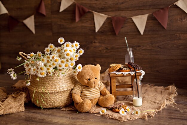 Teddy avec un panier de marguerites, biscuits, lait