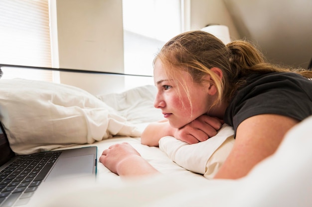 Teen age girl looking at laptop in bed