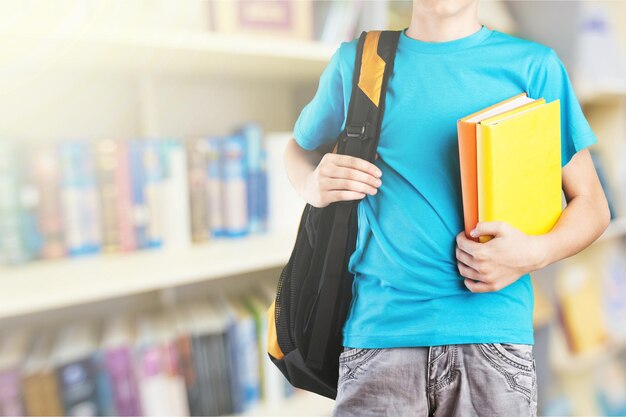 Teen boy avec cartable et livre sur fond