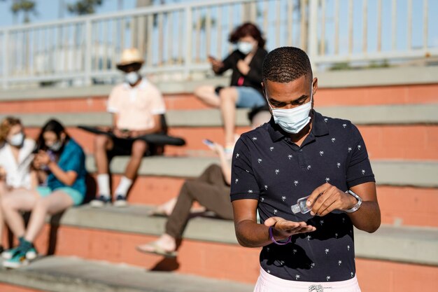 Teen Boy Utilisant Un Désinfectant Pour Les Mains à L'extérieur Dans La Nouvelle Normalité