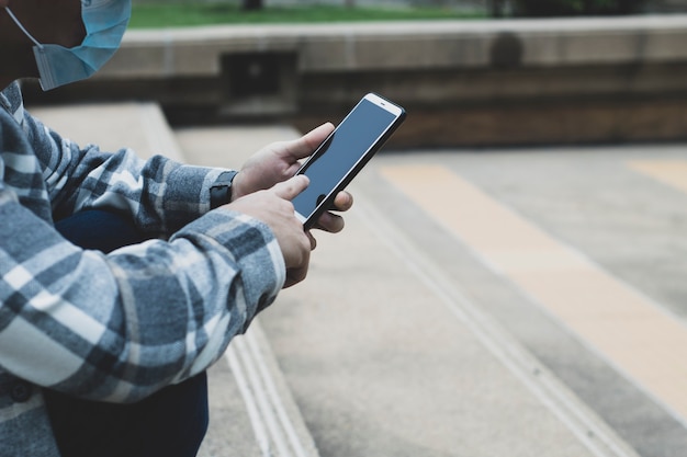 Teen boy utilisant un smartphone pour la technologie de réseau en ligne internet ; l'homme utilise un mobile dans un parc public