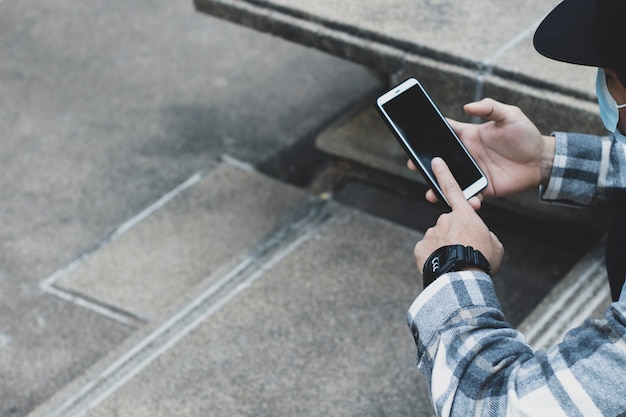 Teen boy utilisant un smartphone pour la technologie de réseau en ligne internet ; l'homme utilise un mobile dans un parc public